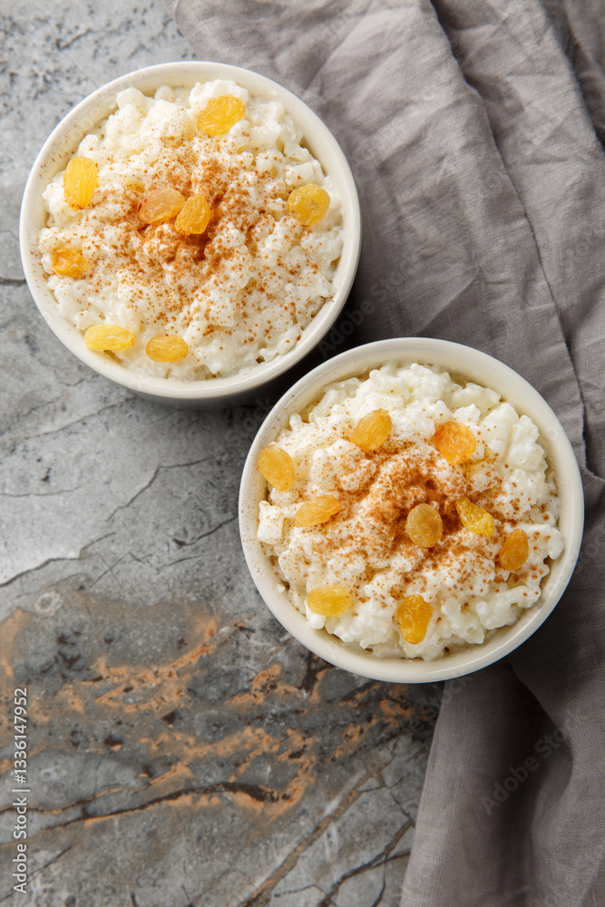 Delicious rice pudding with cinnamon, vanilla and raisins closeup on the bowl on the table. Vertical top view from above