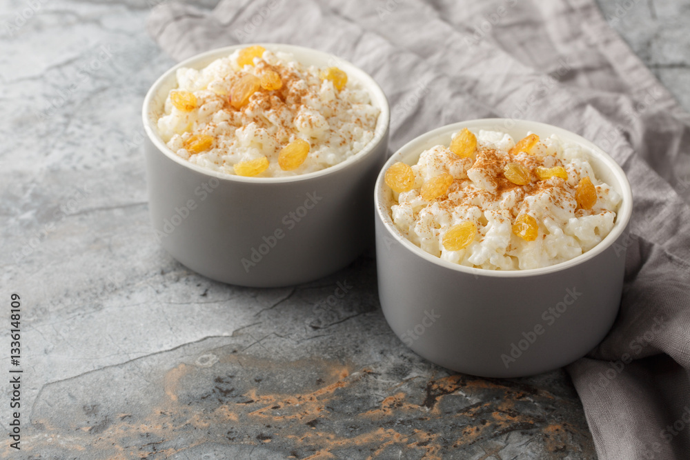 Delicate sweet rice pudding with cinnamon and golden raisins close-up in ramekin on table. Horizontal