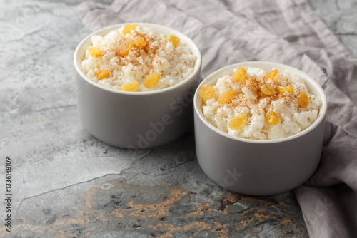 Obraz na płótnie Delicate sweet rice pudding with cinnamon and golden raisins close-up in ramekin on table. Horizontal w salonie