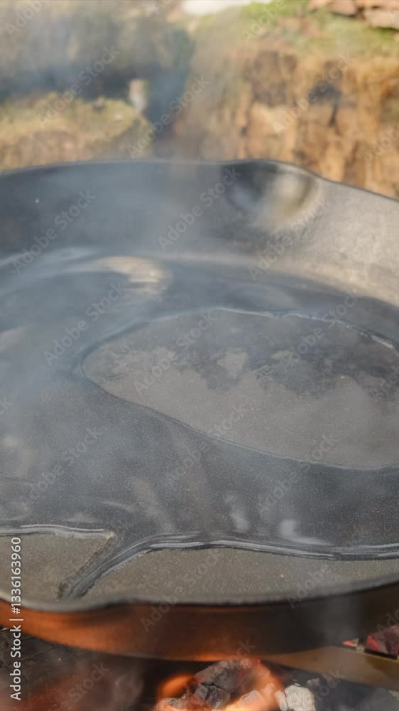 Vertical video of male hand pours olive oil into frying pan on campfire at winter day. Rest and picnic in nature. Cooking outdoors concept. Camping lifestyle routine Vertical video of male hand pours olive oil into frying pan on campfire at winter day. Rest and picnic in nature. Cooking outdoors concept. Camping lifestyle routine