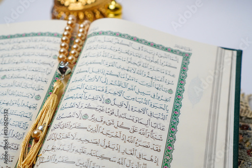 Open Quran with golden prayer beads on a prayer mat