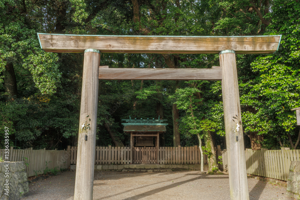 A traditional Japanese Shinto torii gate made of natural wood stands before a lone Hokora, or miniature Shinto shrine, on precincts of parent shrine. A traditional Japanese Shinto torii gate made of natural wood stands before a lone Hokora, or miniature Shinto shrine, on precincts of parent shrine.