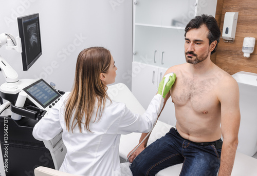 Shoulder ultrasound. Female doctor doing ultrasound scan of male patient with shoulder problem
