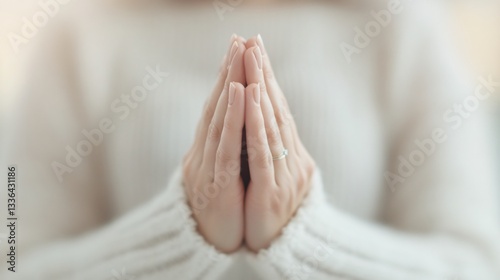 Serene individual in soft sweater, hands pressed together in prayer, evokes calm and mindfulness, perfect for wellness themes.