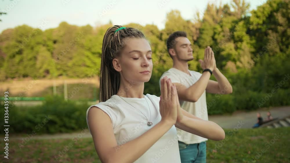Caucasian hipster girl and her boyfriend training together in the park practising yoga asana poses exercises outside. Sport and health concept. Caucasian hipster girl and her boyfriend training together in the park practising yoga asana poses exercises outside. Sport and health concept.
