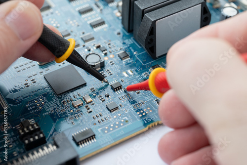 Electronics testing on blue circuit board with multimeter probes
