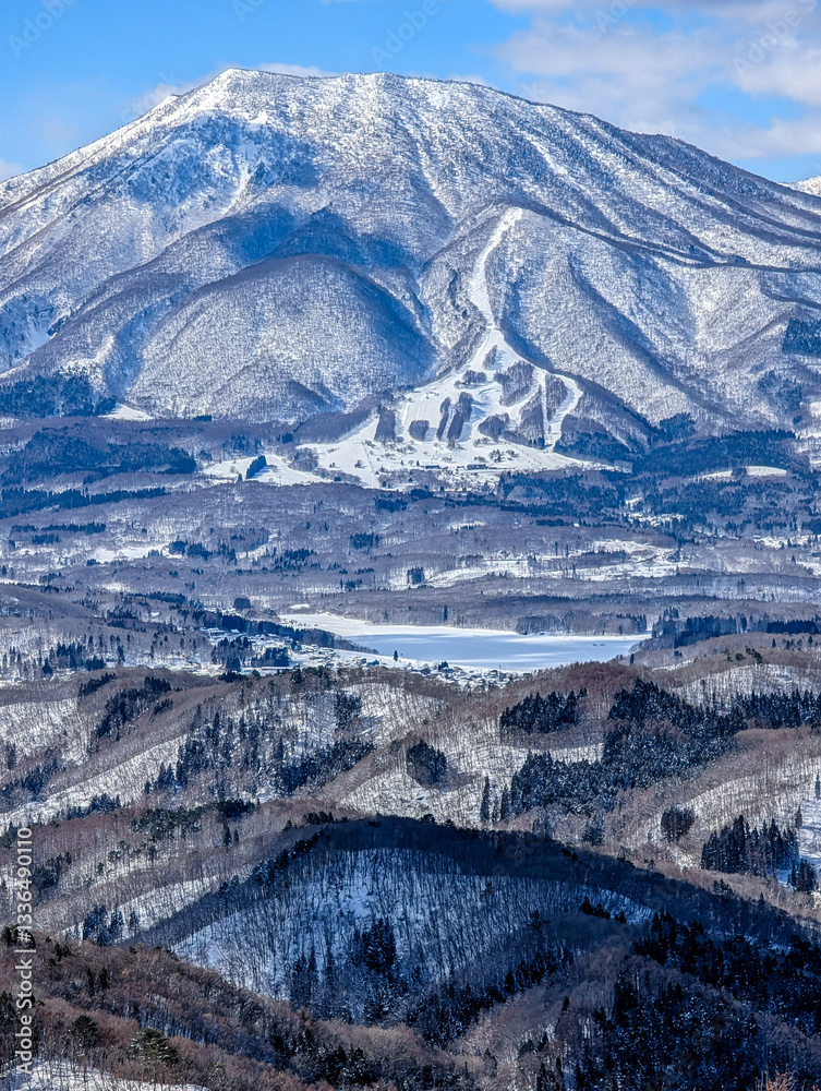 Snow covered winter landscape with blue sky and background mountains