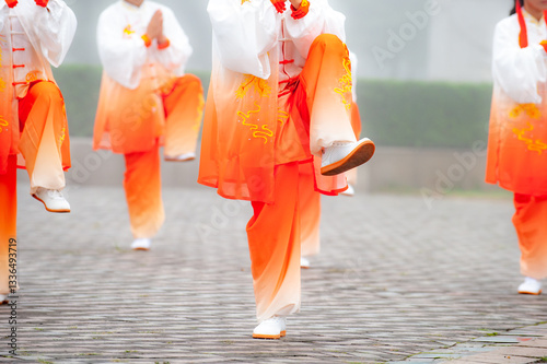 In the foggy morning at the park square, people engage in Tai Chi fitness exercises