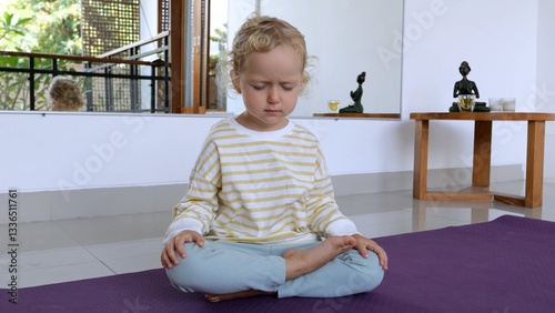 Young practitioner sitting cross legged on purple yoga mat. Practicing mindful meditation with serene expression. Developing inner calm and concentration at home
