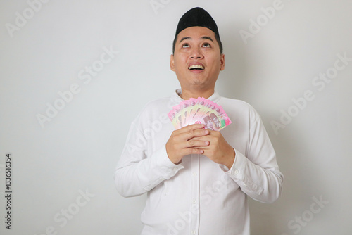 Moslem Asian man smiling happy while holding paper money