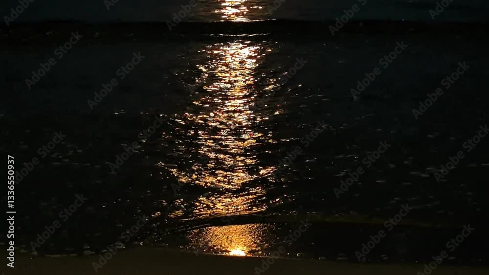 Pleine lune sur la mer Noire. Au clair de lune, les vagues, baignées d'une brillante couleur dorée, glissent vers la plage sablonneuse.