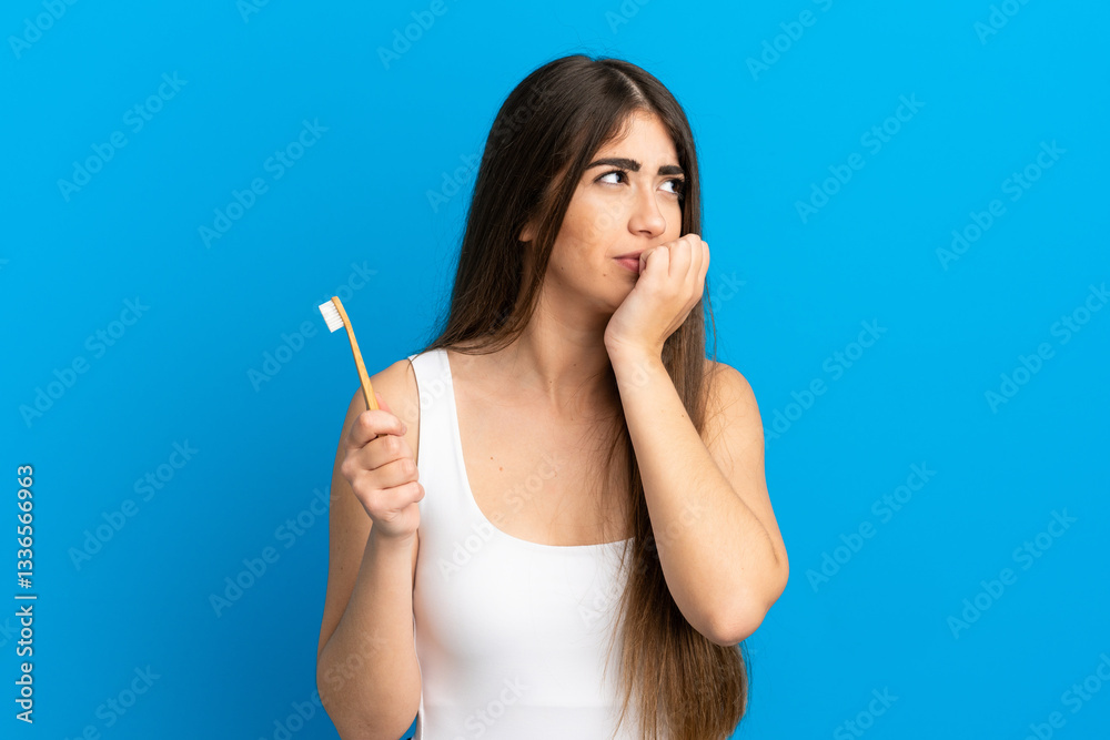 Young caucasian woman brushing teeth isolated on blue background having doubts Young caucasian woman brushing teeth isolated on blue background having doubts