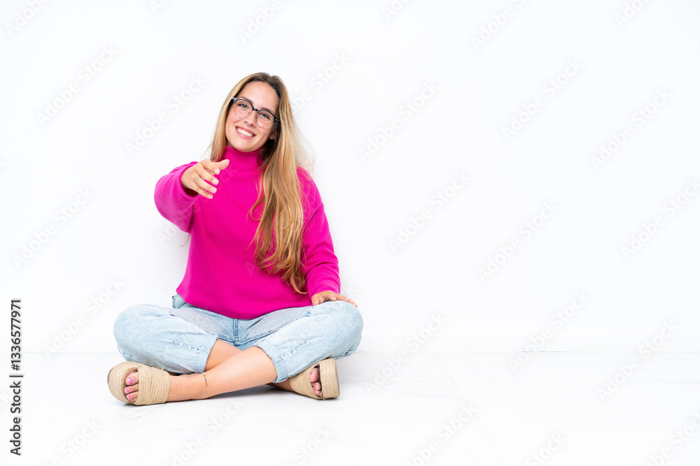 Young caucasian woman sitting on the floor isolated on white background shaking hands for closing a good deal Young caucasian woman sitting on the floor isolated on white background shaking hands for closing a good deal