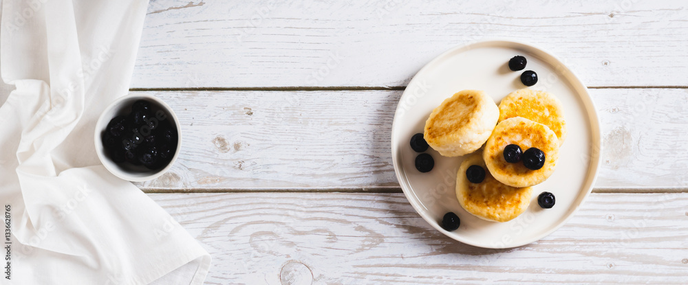 Homemade cottage cheese pancakes and blueberries on a plate on the table top view web banner
