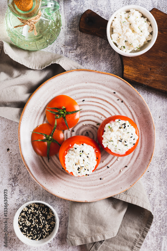 Tomatoes stuffed with cottage cheese and dill on a plate on the table top and vertical view