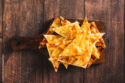 Obraz na płótnie Close up of crispy lavash chips with cheese and garlic on a board on the table top view w salonie
