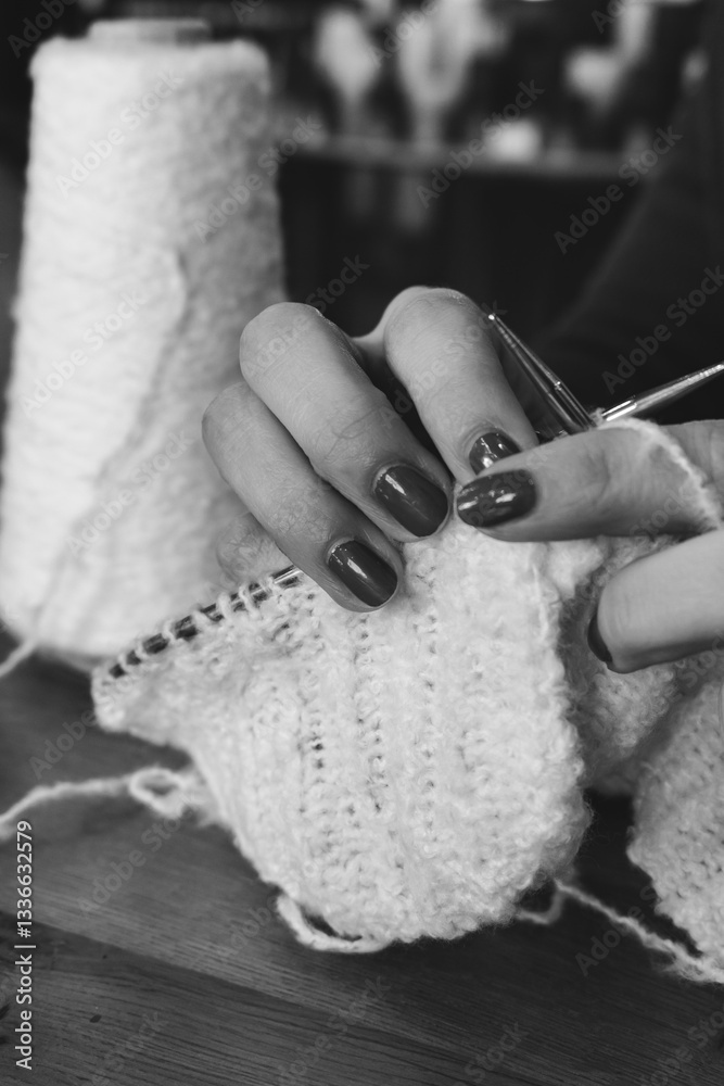Women hands holding knitting needles and knitted work, black and white. Knitting woman with bobbins of yarn and knitwear. monochrome. Needlework in process. Knitting hobby. Knitter work.