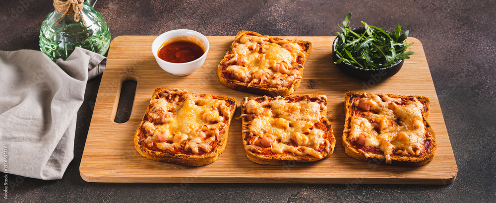 Baked sandwiches with bacon, cheese and tomato sauce on a board on a table web banner