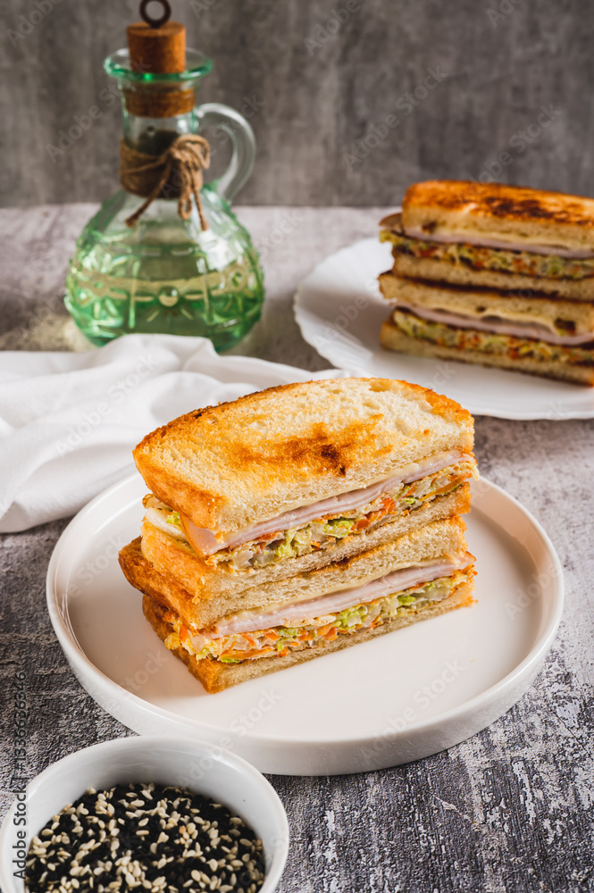 Korean street sandwich with cabbage, ham and cheese on plate on table vertical view