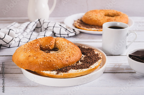 Obraz na płótnie Bagel sandwich with butter and grated chocolate on a plate on a table w salonie