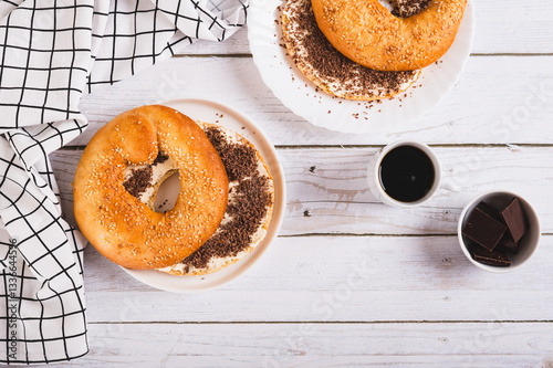 Obraz na płótnie Bagel sandwich with butter and grated chocolate on a plate on a table top view w salonie
