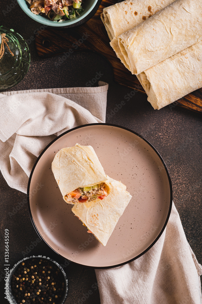 Shawarma in pita bread with meat and vegetables on a plate on the table top and vertical view