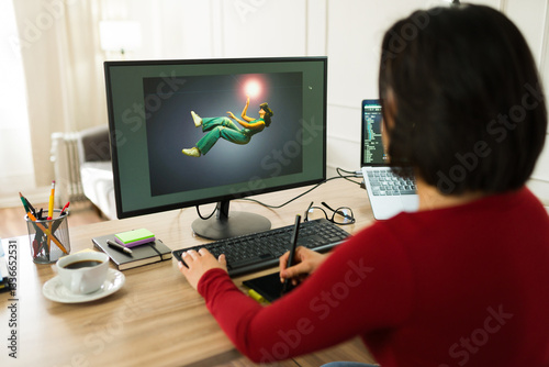 Freelancer immersed in photo editing at home, using a computer and graphic tablet to enhance images in a cozy home office setting