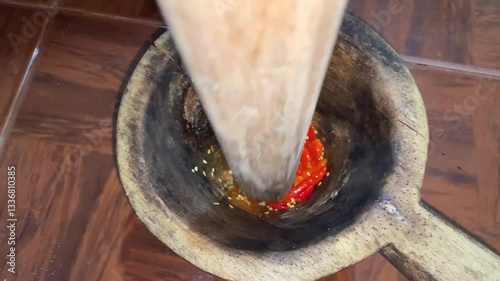 pounding chilies in a traditional tool made of wood. traditional spice crusher. chili grinder. 