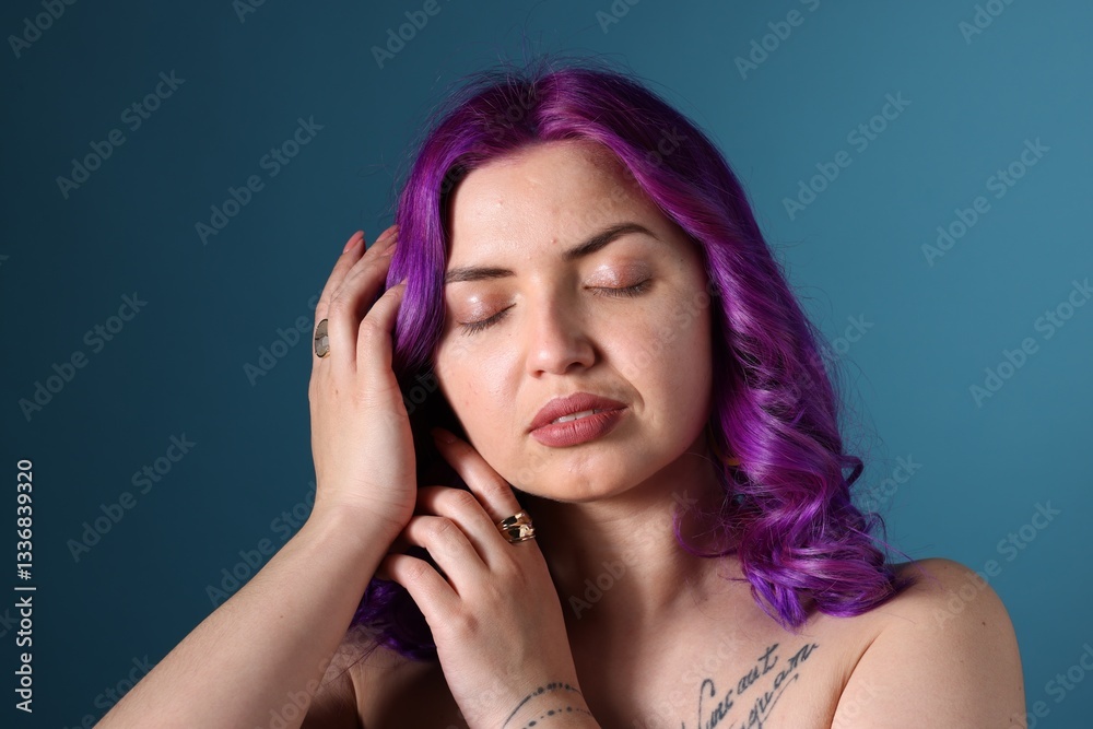 Obraz premium Beautiful woman with bright purple hair and tattoo in Latin on light blue background