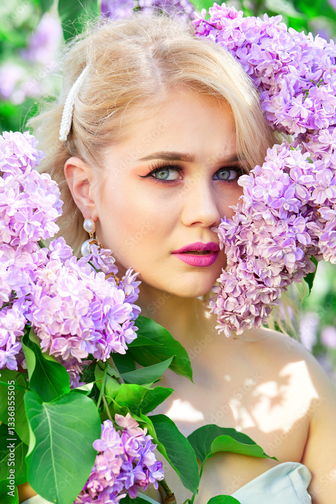Blonde with blue eyes and pink lipstick stands with purple flowers. She is wearing pearl earrings and a pink dress. The image has a soft and romantic mood, with the beauty of the woman. Close-up portr Blonde with blue eyes and pink lipstick stands with purple flowers. She is wearing pearl earrings and a pink dress. The image has a soft and romantic mood, with the beauty of the woman. Close-up portr