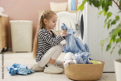 Cute little girl doing laundry at home