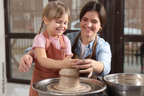 Hobby and craft. Smiling mother with her daughter making pottery indoors