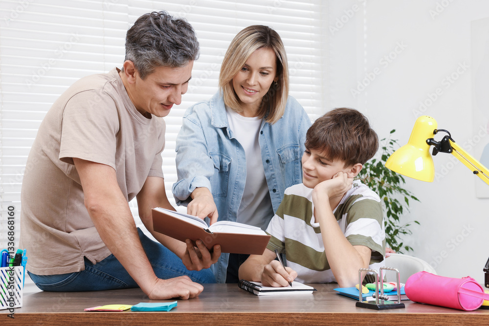 Parents helping their son with homework at table indoors Parents helping their son with homework at table indoors