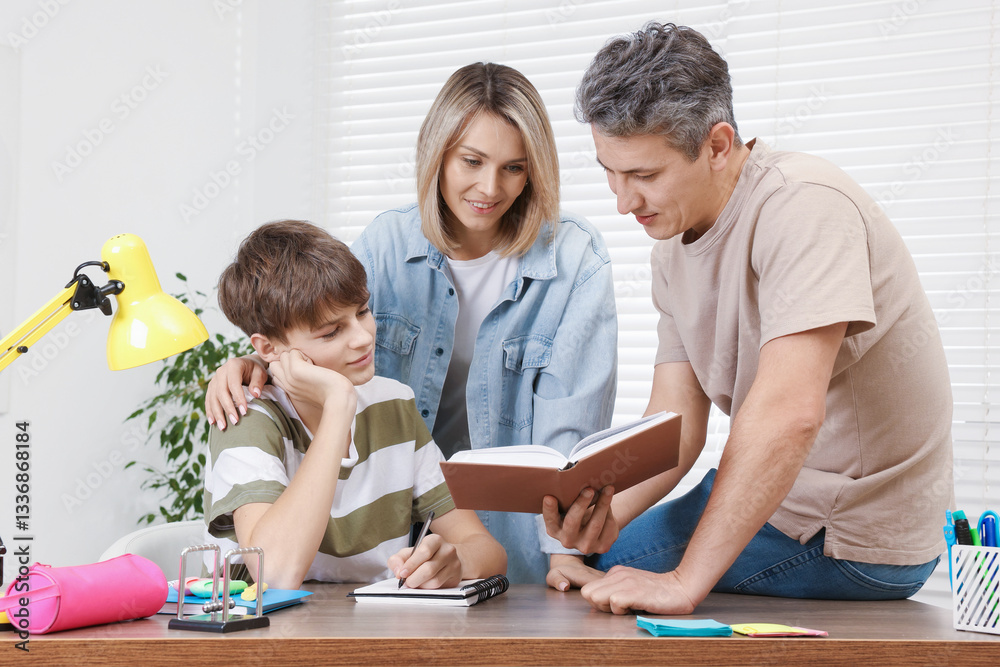 Parents helping their son with homework at table indoors Parents helping their son with homework at table indoors