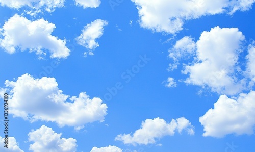 Fluffy white clouds drift across a bright blue sky, creating a calming and serene atmospheric scene