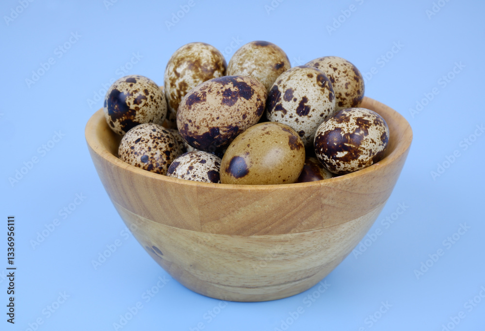 Obraz premium Raw quail eggs in wooden bowl on blue background
