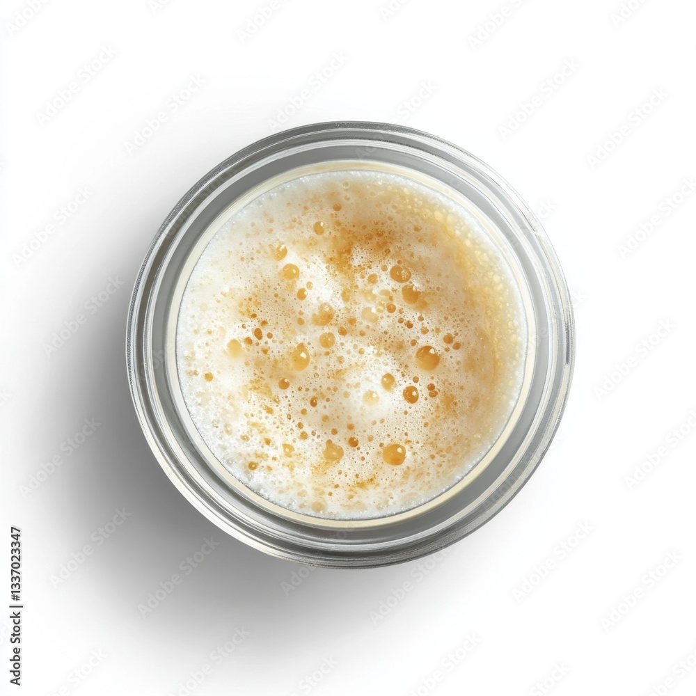 Creamy, frothy beverage in a glass jar. A top-down view of a frothy, light-colored liquid, likely a coffee or tea beverage, in a clear glass jar. The foam is thick and airy, with visible bubbles Creamy, frothy beverage in a glass jar. A top-down view of a frothy, light-colored liquid, likely a coffee or tea beverage, in a clear glass jar. The foam is thick and airy, with visible bubbles