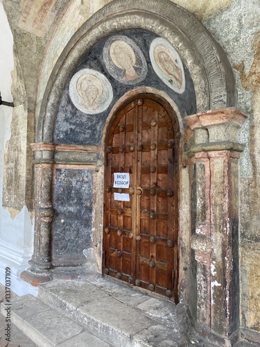 Old wooden door in an arched entrance of a historical building  showing discoloration and wear    