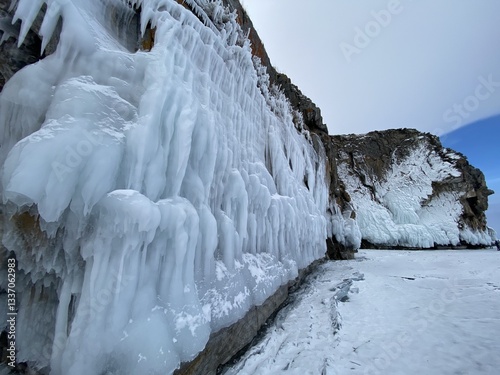 A waterfall frozen on a snow-covered rocky cliffside     