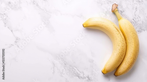 Two ripe yellow bananas on a marble surface