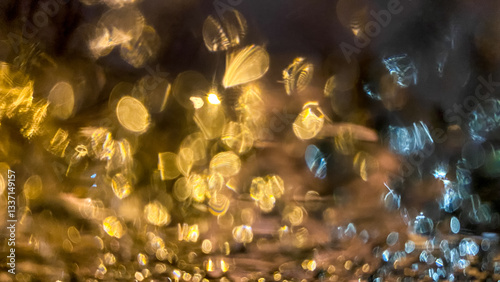 Yellow bokeh effect in night or evening street lighting on car glass in frost. Winter abstract background. A drop of water on the window. The lights are out of focus.