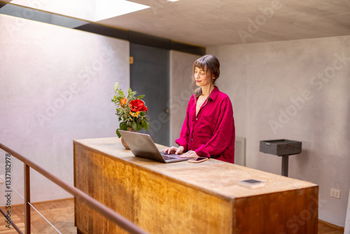 Obraz na płótnie A stylish woman in red leans over a wooden desk, engaged in work on her laptop. The setting embodies focus, creativity, and modern remote work culture in a cozy, minimalist home environment w salonie