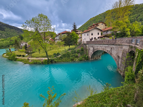 Fotografie Turquoise soča river meandering under stone arch, flowing past verdant landscape