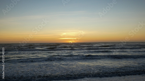 Tranquilo atardecer sobre el océano con cielo dorado y suaves olas