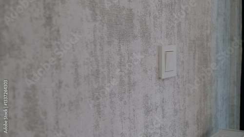 Turning Light Switch On and Off with a Gentle Touch on a Stylish Wallpapered Wall – Close-Up Hand Action