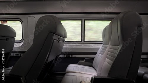 View of empty train seats and landscape passing through a train window.