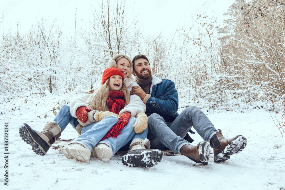 Obraz premium Cute young family having fun in a winter forest and looking enjoyed