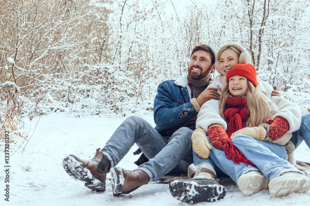 Obraz premium Cute young family having fun in a winter forest and looking enjoyed
