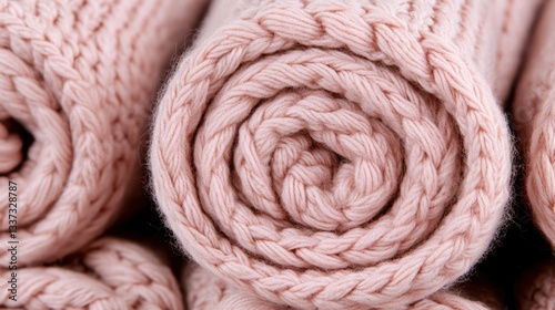 Delicate pink knitted scarves rolled perfectly, showcasing craftsmanship and cozy elegance, inviting warmth and sophistication.