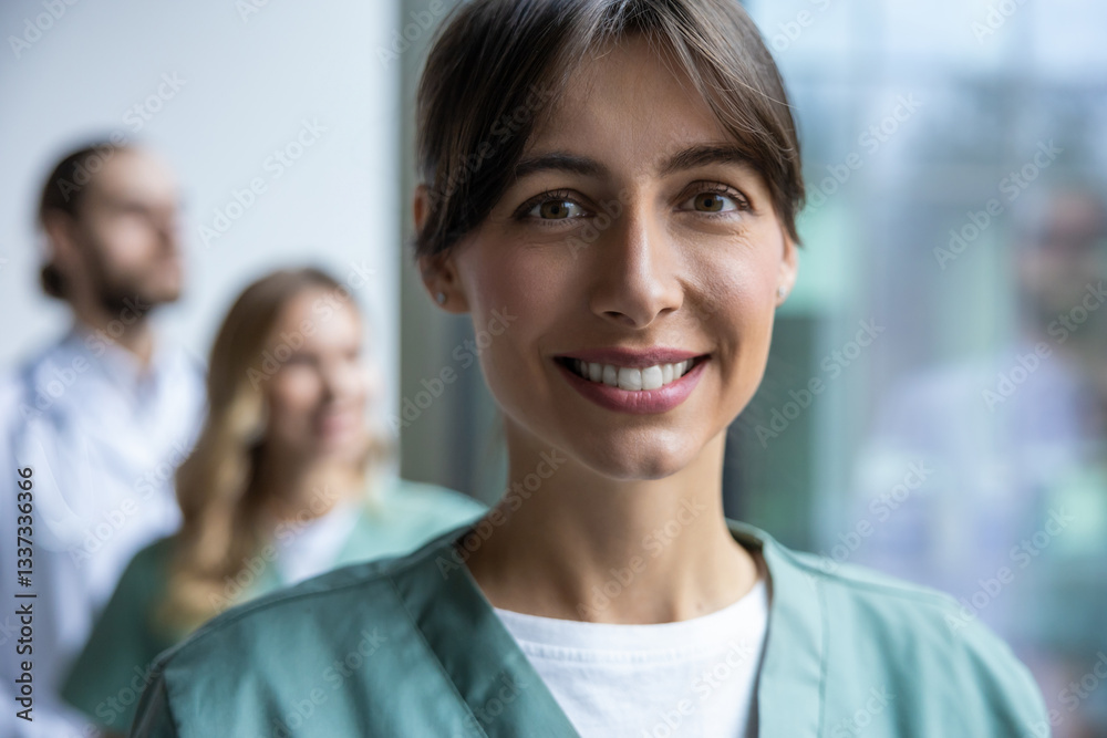 Woman doctor in medical uniform posing in clinic office hall with medical workers on background Woman doctor in medical uniform posing in clinic office hall with medical workers on background